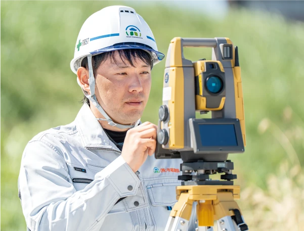 現場で測量機器を操作する土木技術者のYさん